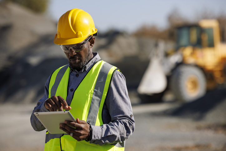 Portrait of male engineer with hardhat using digital tablet while working at construction site