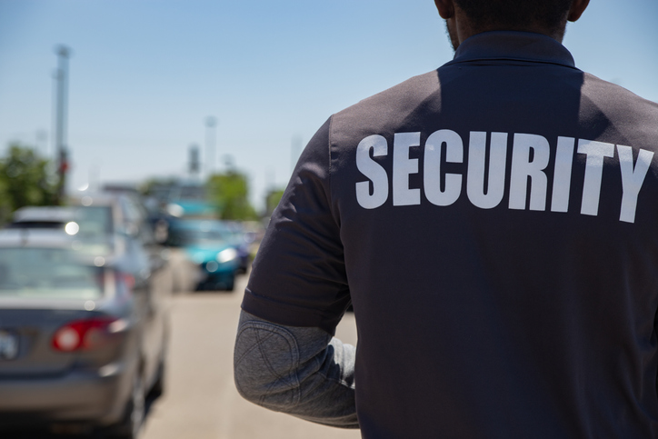 A rear view of parking security watching over parking area. Security guard is protecting property from illegal parking and theft.